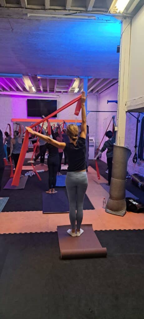 Cours de Fitness avec Bandes de Résistance en Studio Séance de fitness avec bandes de résistance rouges dans un studio de sport moderne aux lumières néon bleues et violettes.