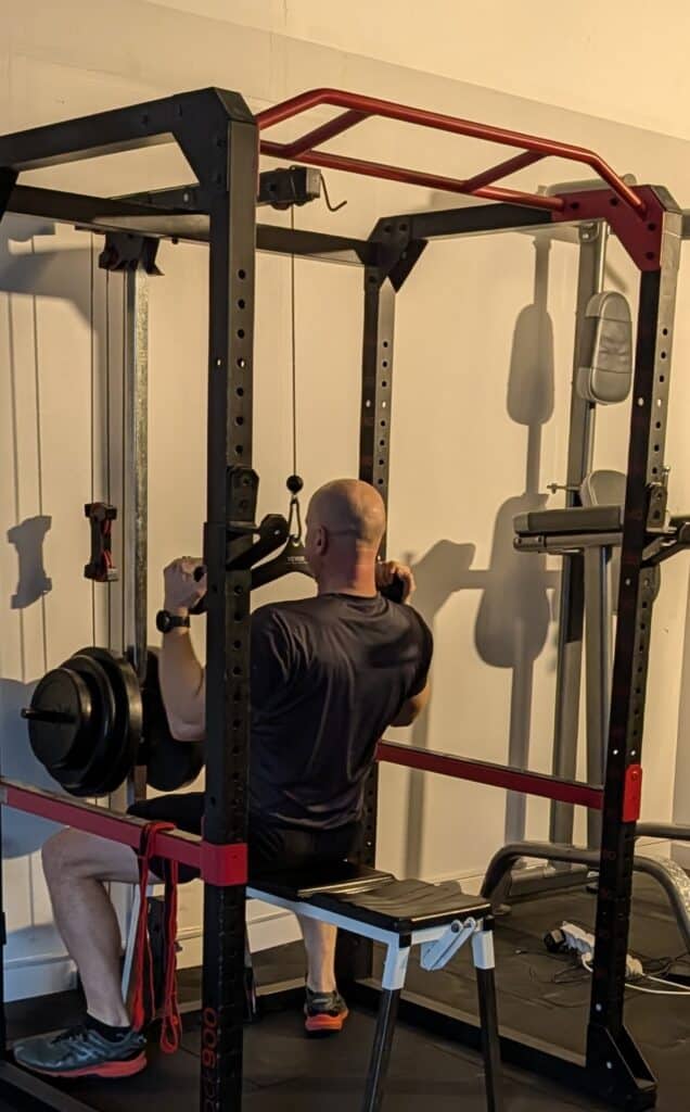 Tirage vertical dos sur Rack 900 : Musculation à domicile Homme faisant des tirages verticaux sur un Rack 900 avec attache VEVOR dans une salle de musculation à domicile.